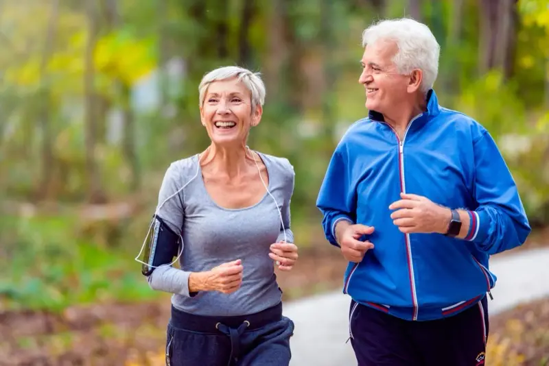 Happy senior couple jogging together outdoors staying active with joint health